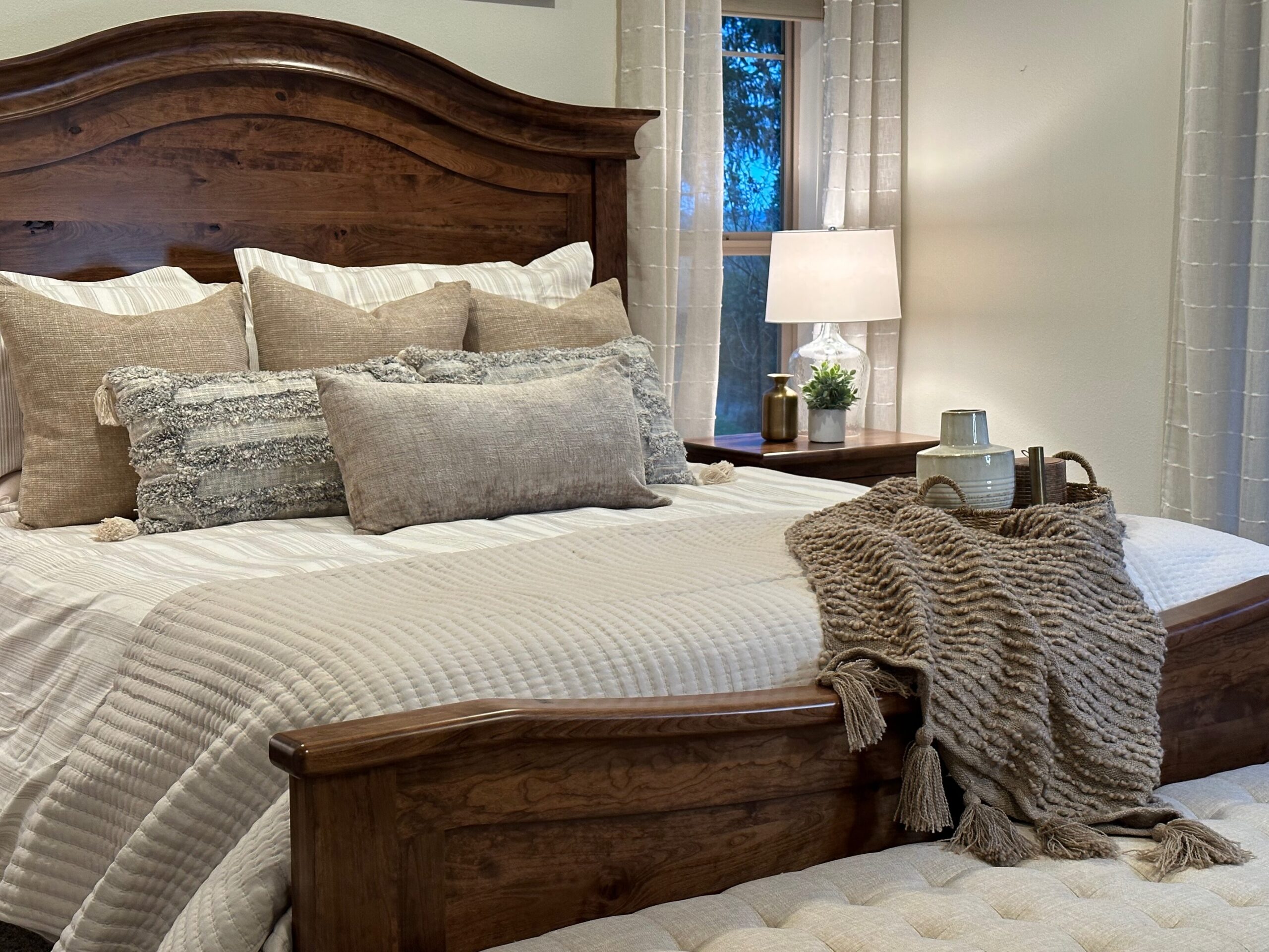Primary suite bedroom styled by interior designer with bed frame, bedding, bench, nightstands and lamp